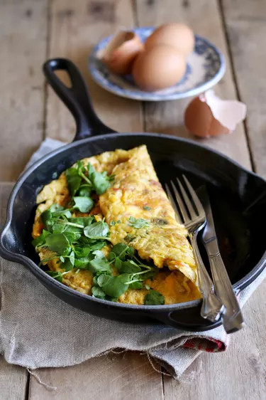 Homemade omelet with watercress on wooden background