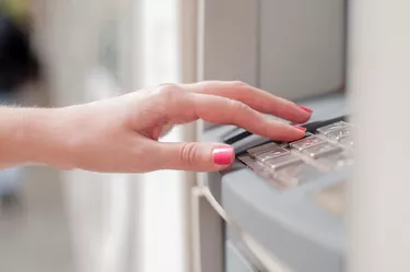 Close up of hand entering pin at an ATM.