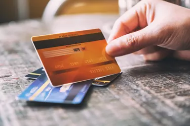 Close-Up Of Cropped Hand Holding Credit Card At Table