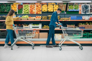 man and a woman with shopping carts in a supermarket during the quarantine period