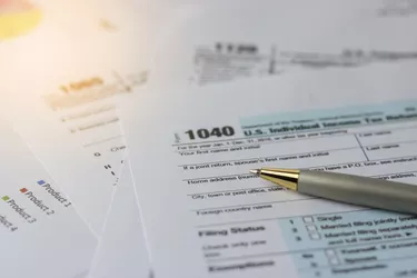 Selective focus a pen on US tax form 1040 on top for background / taxation concept