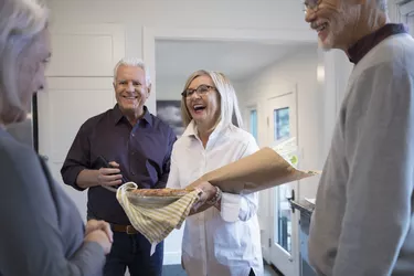 Senior couple with flowers and pie arriving at dinner party