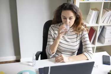 Freelancer young woman working at home and drinking water