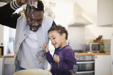 Playful father and son baking in kitchen