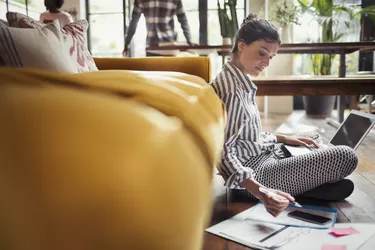 Female freelancer working at laptop on living room floor