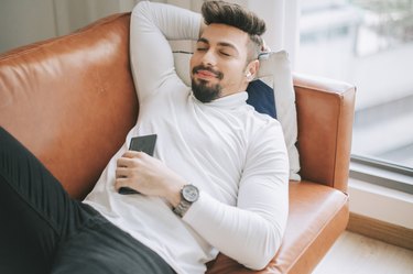 a middle eastern man lying down on sofa in living room relaxing taking a break in the afternoon