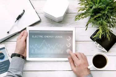 Man holds tablet pc with electric energy usage application.