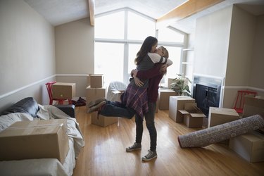 Affectionate, playful lesbian couple hugging and kissing, moving into new house