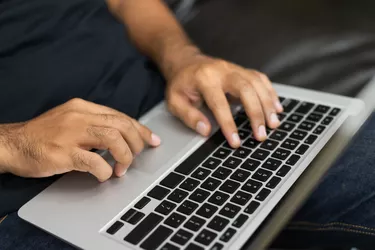 Close up male hands using laptop work from home sofa