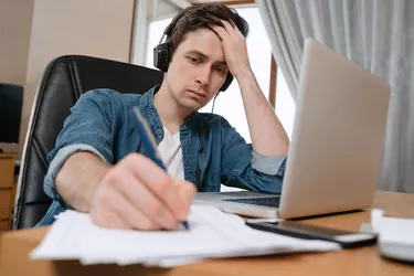 Freelancer wearing headphones working remotely with laptop