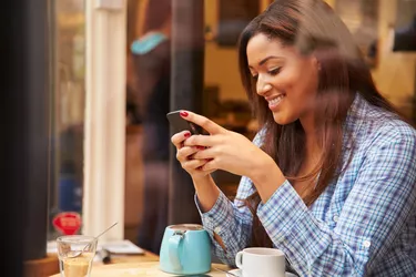 Woman Viewed Through Window Of Cafe Using Mobile Phone