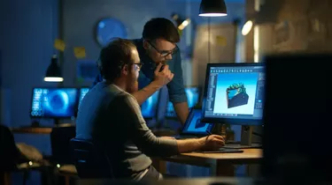 Two Male Game Developers Discuss Game Level Drawing, One Uses Graphic Tablet. They Work Late at Night in a Loft Office.