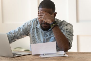 Stressed upset african american reading bad news in letter.