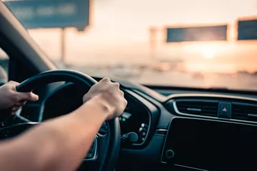 Hand of man driving car on the road.