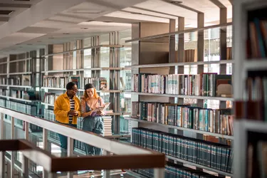 Female students talking about a book in a library