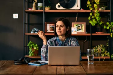 Mid adult businesswoman using laptop and looking away