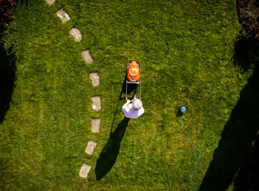 Aerial view of man mowing the grass with lawn mower in the garden