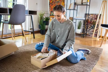 Young woman unpacking package that she have received after online shopping