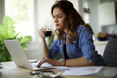 Young woman drinking coffee and working at home