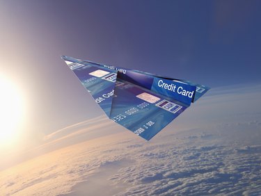 Credit card folded into paper airplane in atmosphere