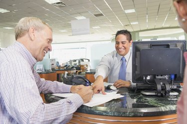 Salesman helping couple sign paperwork in car dealership