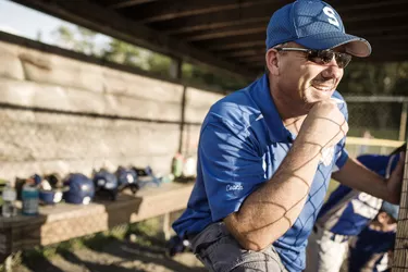 Coach smiling while standing in dugout