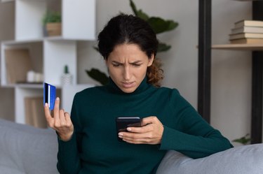 Concerned lady looking on smartphone having finance stolen from card