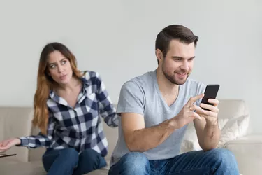 Jealous suspicious wife arguing with obsessed husband holding phone