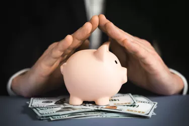 Money Protecting concept. Saving symbol - Close-up Of A Human Hand Protecting Pink Piggy Bank