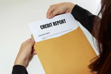 Cropped Hands Removing Credit Report From Envelope At Table