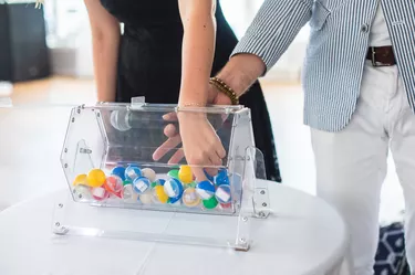 Process of prize drawings, extracting a winning numbers of lottery machine, raffle drum with bingo balls and winning tickets on event with a host and hands on lottery machine