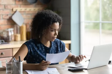 Serious millennial African American woman calculating taxes