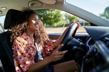 Smiling young woman driving car