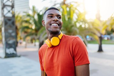 Happy man with headphones standing in the street while looking away