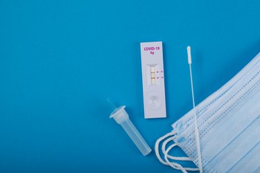 Rapid test for Covid-19 Coronavirus, positive result. Laboratory kit for self-testing at home. Blue paper background, copy space