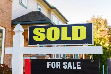 Sold sign against a house in a residential neighborhood