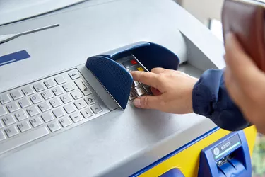A female hand dials a personal code on the ATM keyboard. The concept of safe use of bank cards, deductible funds, the wholesale of services and goods, receiving cash. Close-up