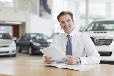 Car salesman with paperwork at desk