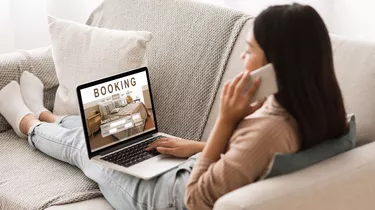 Girl booking hotel online, talking on phone with reservation team