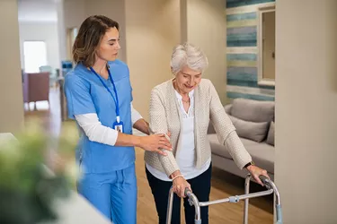 Nurse helping senior woman to walk at private clinic