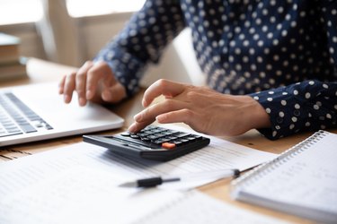 Close up Indian woman planning budget, using calculator and laptop