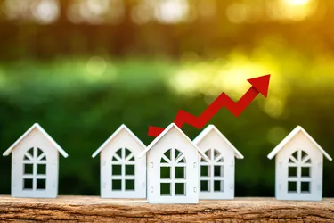 Home model and red arrow graph with growing value put on the wood in the public park, Business investment the real estate concept.