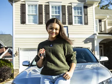 Portrait of teenage girl with her first car