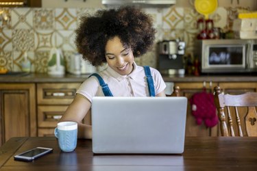 Portrait of a young afro woman surfing the net in the kitchen