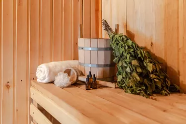 Traditional old Russian bathhouse SPA Concept. Interior details Finnish sauna steam room with traditional sauna accessories set basin birch broom towel aroma oil. Relax country village bath concept