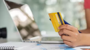 Business women hold credit cards and use laptop computers and mobile phones to shop online, e-commerce, internet banking, spend money, work from home.