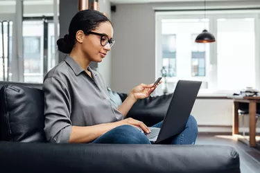 Young woman making online payment while sitting in the living room on sofa