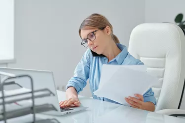 Busy secretary of brokerage company calling client and working with papers