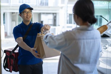 smiling delivery man delivers food to a woman standing at the door.