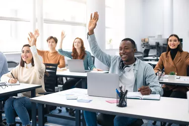 Portrait of smiling diverse people raising hands at seminar